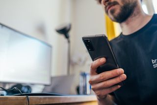 A man looks up from reading Bible In One Year on his phone.