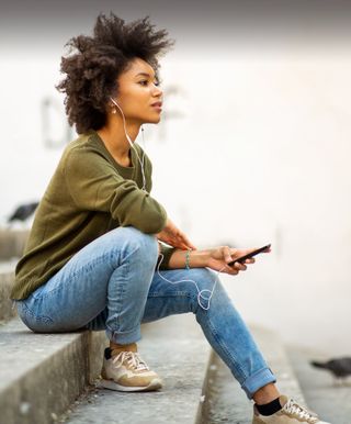 A woman looks up from reading Bible In One Year on her phone.